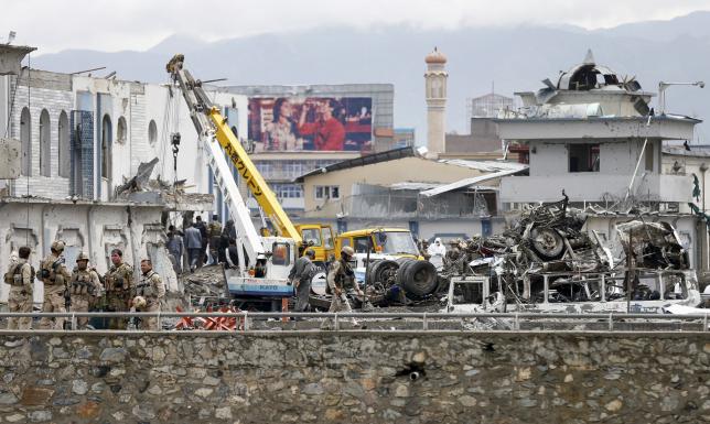 Afghan security forces inspect the site of suicide car bomb attack on a government security building in Kabul, Afghanistan